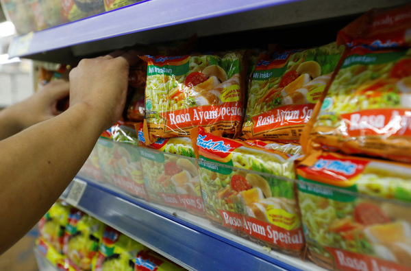 A worker arranges Indomie's Special Chicken Flavour instant noodles packets on the shelves of a supermarket in Jakarta, Indonesia on 26 April 2023.