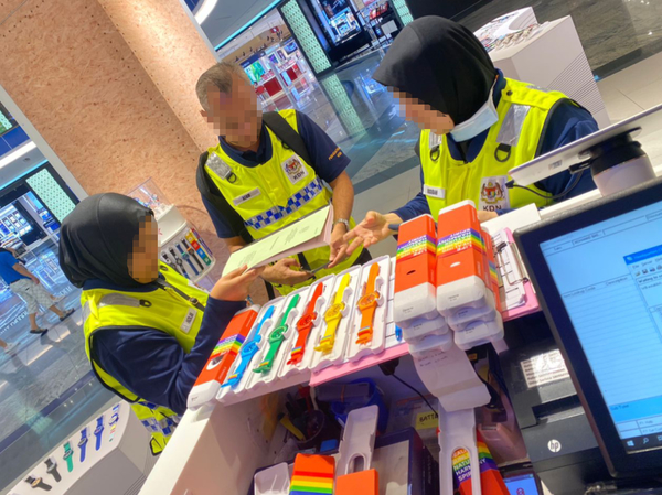 Ministry of Home Affairs officers are pictured with seized Swatch watches at Southkey Mall in Johor.