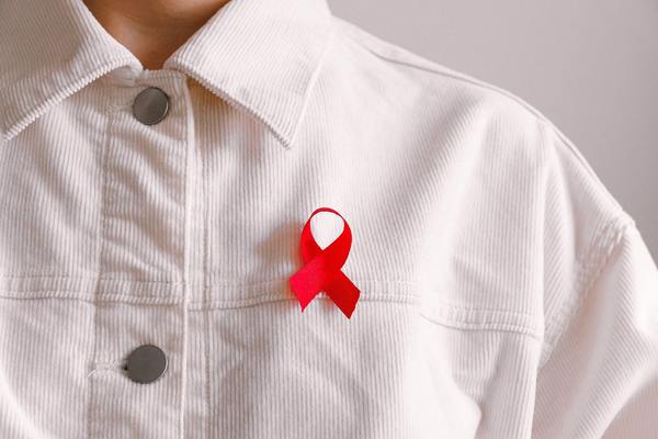 A red ribbon, which has become an international symbol for AIDS awareness and is worn in support of people living with HIV (PLHIV).