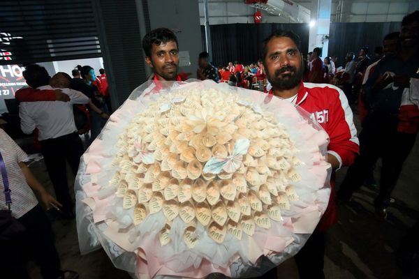 Winner Selvam Arumugam (right) with a bouquet of SGD18,888 in cash.