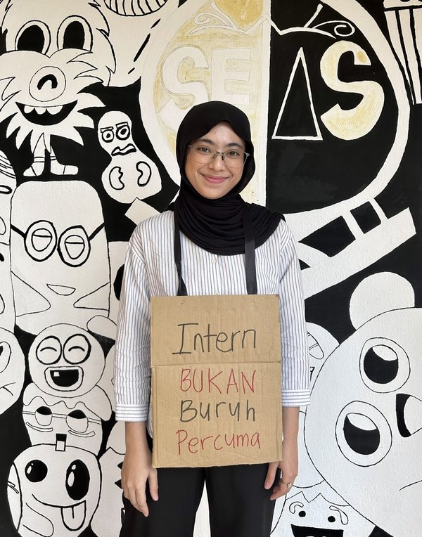 Rashifa Aljunied wearing the "Interns are not free labourers" placard.