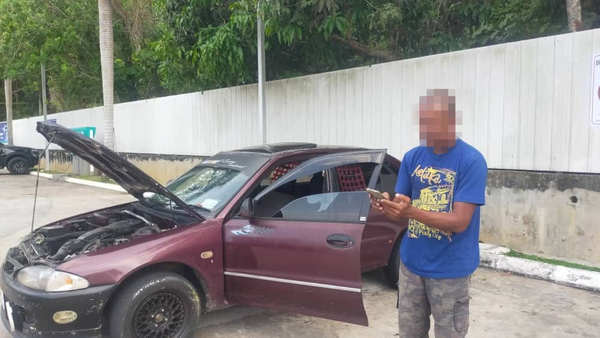 Razak checks his phone beside the car in which he and his family has been living.