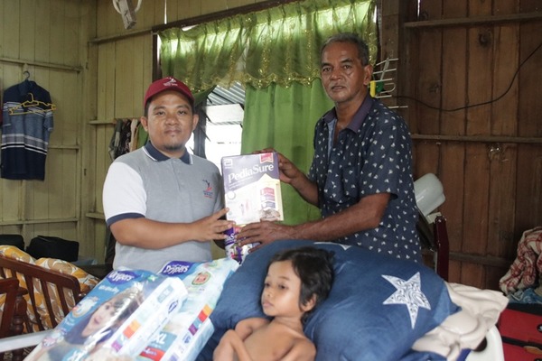 Wakil  Yayasan Ikhlas, Mohd Khairul Ahmad Nordin menyerahkan bantuan kepada bapa adik Hafiz.