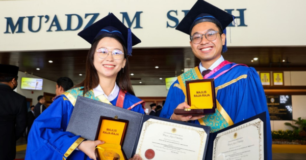 Wong Wei Ji holding the Royal Education Award alongside another recipient, Ahmad Afiq Iqmal Ahmad Said, at UUM's 35th Convocation Ceremony.