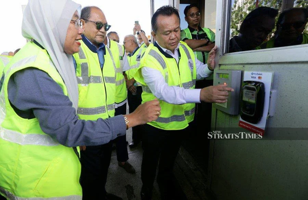 Works Minister Datuk Seri Alexander Nanta Linggi (right) at the launch of the new payment system at MEX's Putrajaya toll plaza.