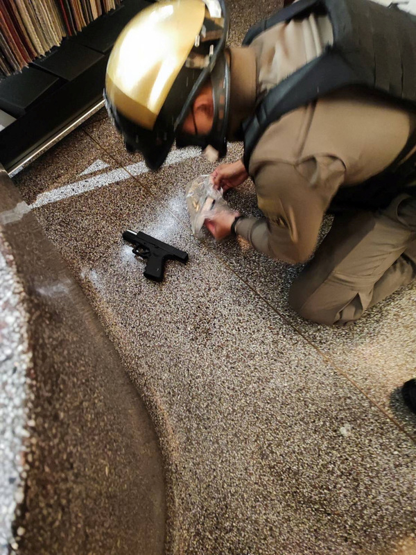 A police officer collects a gun after the suspect was arrested.