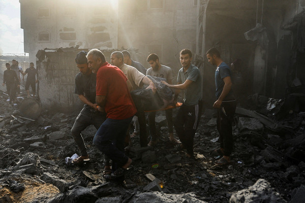 Palestinians carry a casualty on rubble in the aftermath of Israeli strikes, in Khan Younis in the southern Gaza Strip on 11 October.