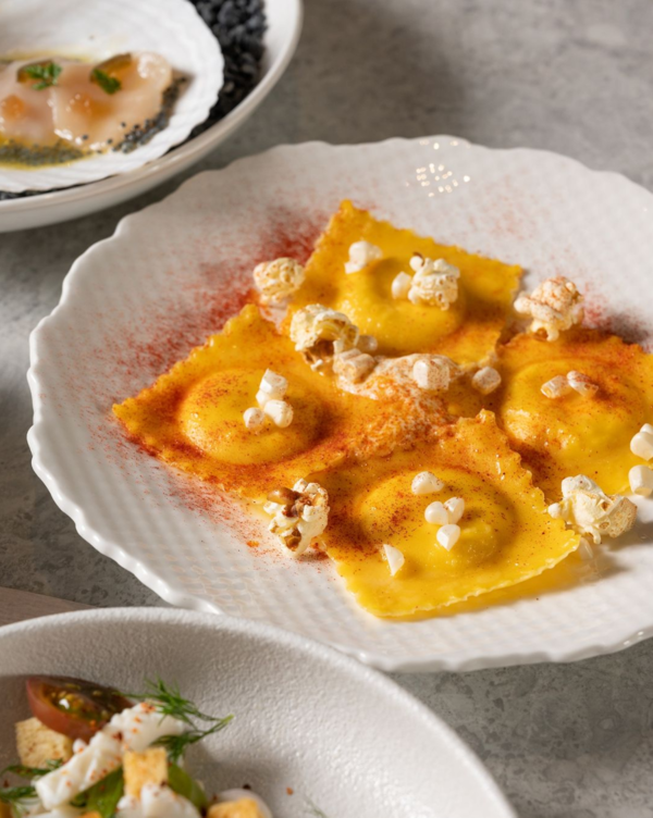 White Corn and Gorgonzola Ravioli with a dusting of Paprika and topped with Popcorn.