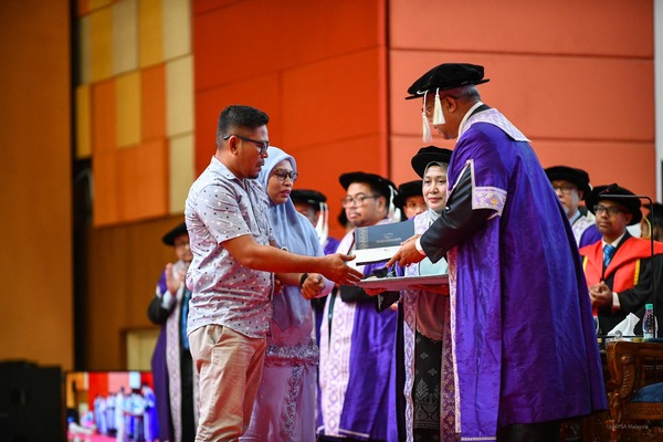 Asniza's parents receiving her scroll from UMPSA vice-chancellor Professor Datuk Dr Yuserrie Zainuddin at the ceremony on Sunday, 22 October.