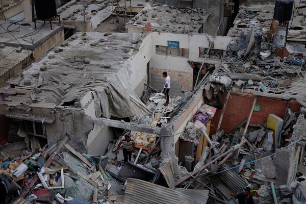 Palestinians check the damage at the site of Israeli strikes on houses.