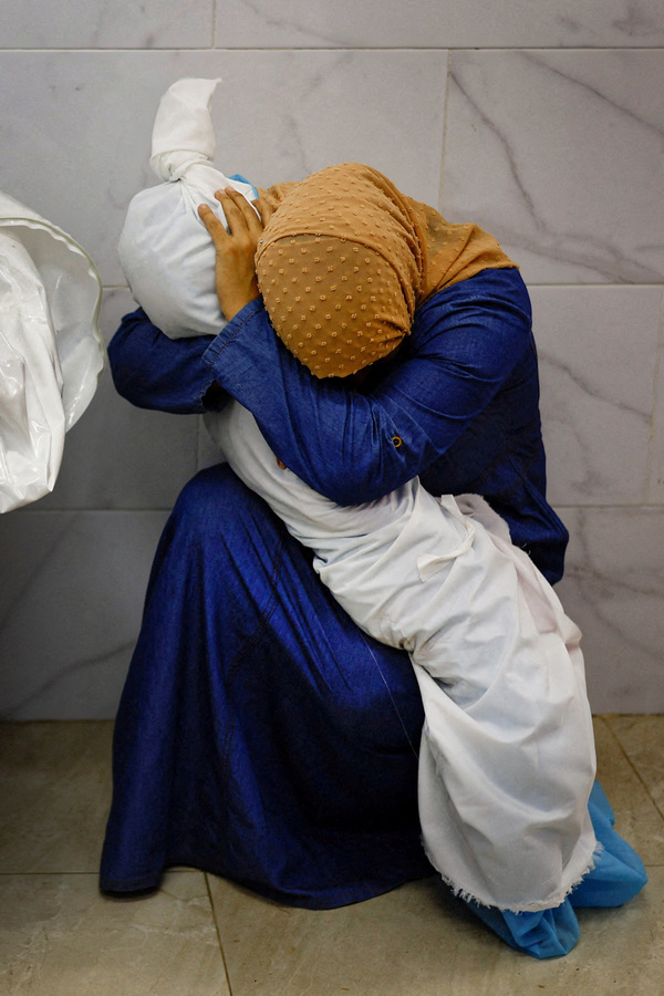 Palestinian woman Inas Abu Maamar, 36, embraces the body of her five-year-old niece Saly, who was killed in an Israeli strike, at Nasser hospital in Khan Younis in the southern Gaza Strip, 17 October.