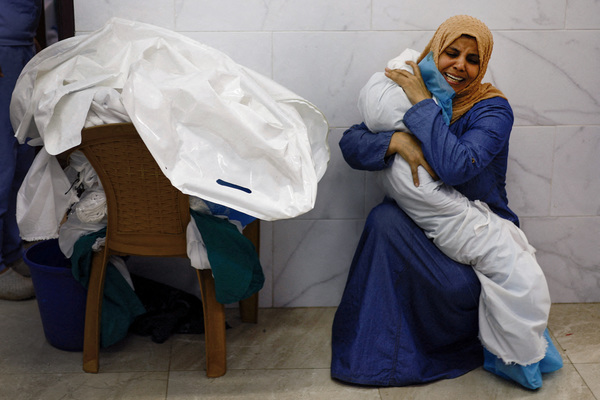 Inas Abu Maamar embraces the body of her five-year-old niece Saly, who was killed in an Israeli strike, at Nasser Hospital in Khan Younis in the southern Gaza Strip, 17 October.