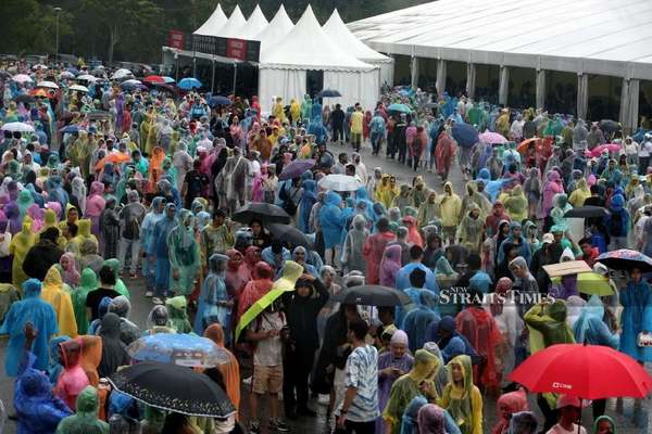 Concertgoers lining up under the rain to enter Bukit Jalil National Stadium on Wednesday, 22 November.