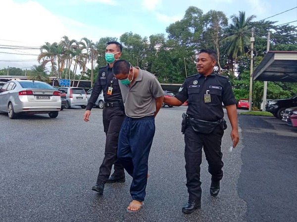 The accused, Harma Zulfika Deraman, being escorted by police.