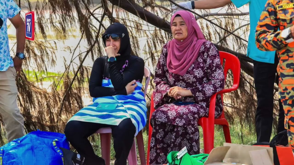 44-year-old Nora Elina Abdul Khalil (left) crying while firefighters searched for her missing husband at Pantai Batu Buruk.