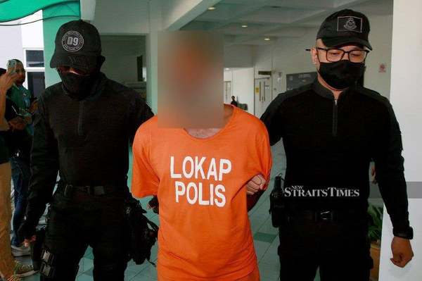 The accused is seen being escorted at the Shah Alam Court Complex ahead of his trial.