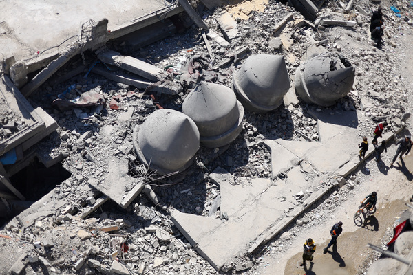 Palestinians walk on the day of the first Friday prayers during Ramadan near the ruins of a destroyed mosque.