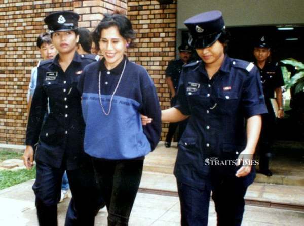 Mona Fandey being escorted by police officers in Kuala Lumpur.