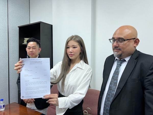 Ms Puiyi holding the civil suit documents with her lawyer K Mahendren next to her.