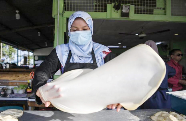 A woman making roti canai.