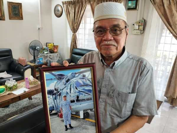 Mohd Termizi holding a photo of the late Mohd Shahrizan Mohd Termizi.