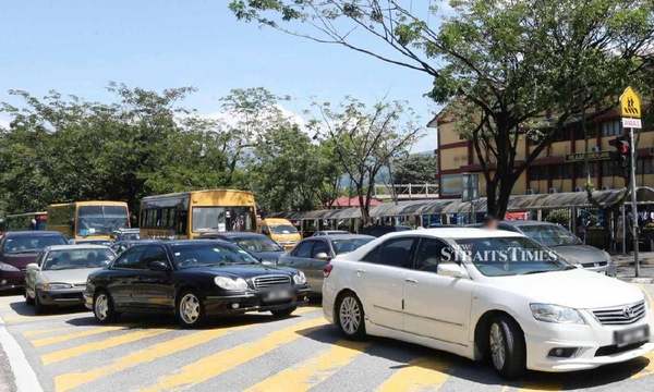 Parents parking their cars in the middle of the road causes traffic congestion during school drop-off hours.