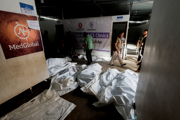 People walk near the bodies of Palestinians killed in an Israeli strike on an area designated for displaced people, during their funeral in Rafah, in the southern Gaza Strip.