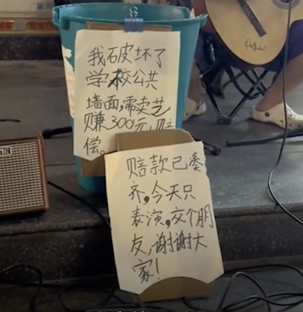 The sign next to the boy's music stand reads, "I damaged the school wall and need 300 yuan (RM195) to fix it."