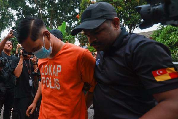 The suspect being escorted by the police to the Kuala Kubu Bharu Magistrate's Court complex today, 16 July.