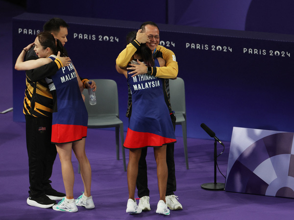 Tan and Thinaah give their coaches a hug after the quarter-finals match.