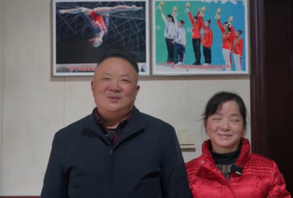 Zhou's father and mother standing in front of photo frames of their daughter.