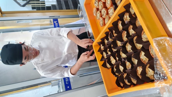 A SEGi College culinary student carefully packs cempedak muffins during a previous project, ensuring each one is ready for distribution to the Salvation Army's Children's Home.