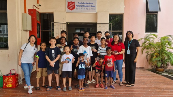 Leong Mi-Chelle (left), Principal of SEGi College, the boys from the Salvation Army Children's Home, Sharon Tong (right) founder of Access to Excess, and staff members gather for a group photo after receiving their cempedak muffins.