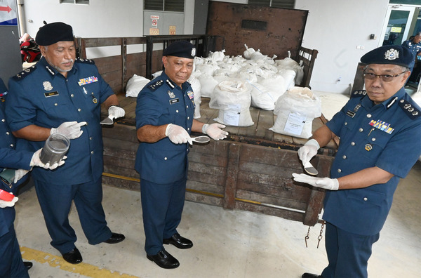 Nadzri (centre) displaying the 5,000kg of tin ore powder believed to have been smuggled from Indonesia last month.