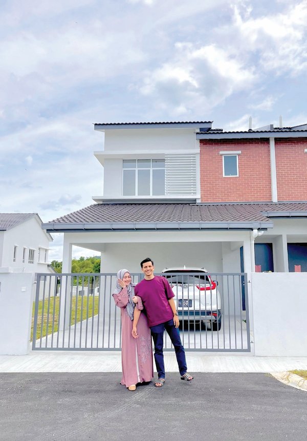 The couple posing in front of their new home.