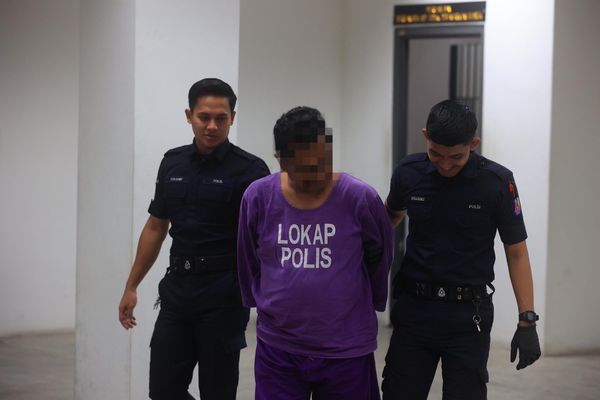 The bomoh being escorted by two policemen outside the Kota Bharu Magistrate's court today, 25 September.