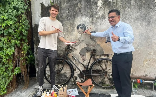 Ernest Zacharevic and Penang state tourism and creative economy committee chairman Wong Han Wai posing in front of 'Children on a Bicycle' on Armenian Street.