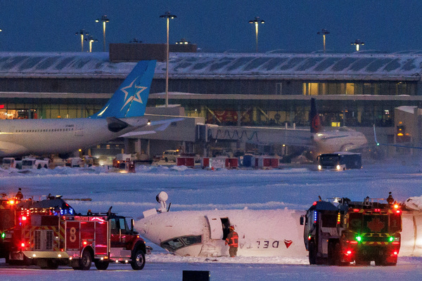 Emergency responders operate around a plane on a runway after a plane crash at Toronto Pearson International Airport in Mississauga, Ontario, Canada on 17 February.