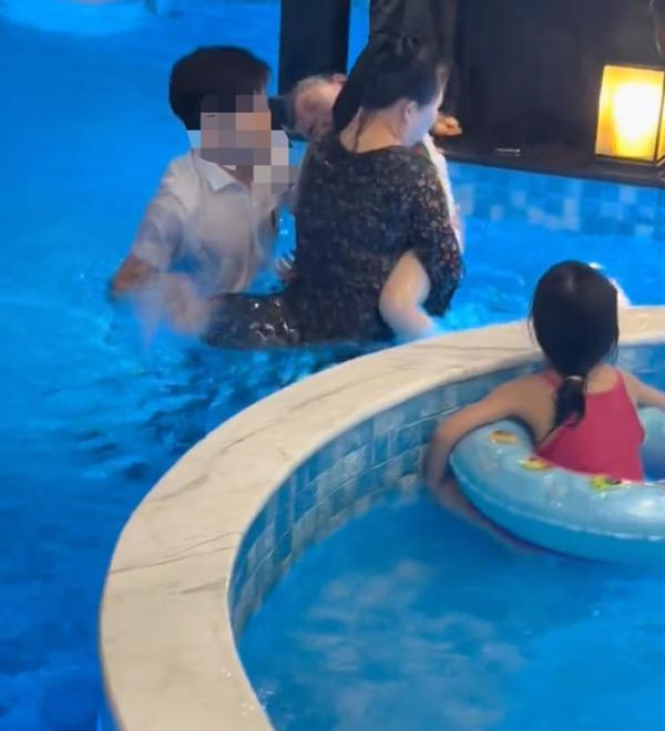 The little girl's mother carrying her daughter out of the pool.