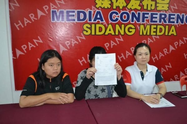 The victim (centre) holds up the police report lodged in Sarikei. On her right is MP Alice Lau.