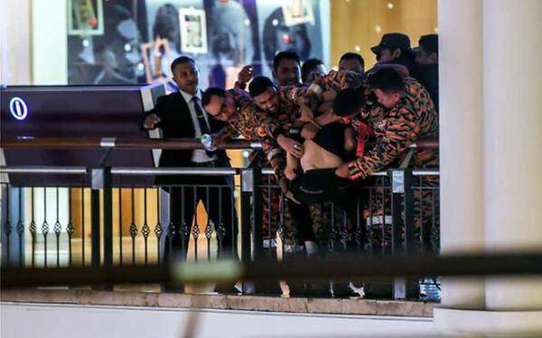 This Bernama photo shows Fire brigade personnel grabbing the man after spending more than two hours to try and talk him out of committing suicide.