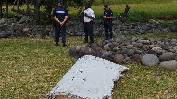 French gendarmes and police stand near a large piece of plane debris which was found on the beach in Saint-Andre, on the French Indian Ocean island of La Reunion. Taken 29 July, 2015.