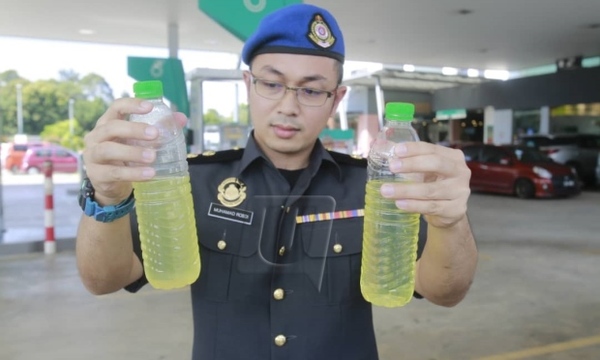 A KPDNHEP officer holds up samples taken from the petrol station.