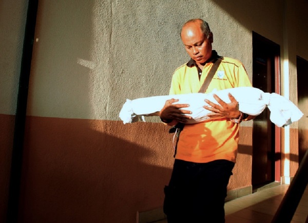 Supian Samsuri cradles the body of his daughter Nur Qhaisara Medina as he leaves the Forensic Unit of Raja Permaisuri Bainun Hospital in Ipoh on February 17, 2019.