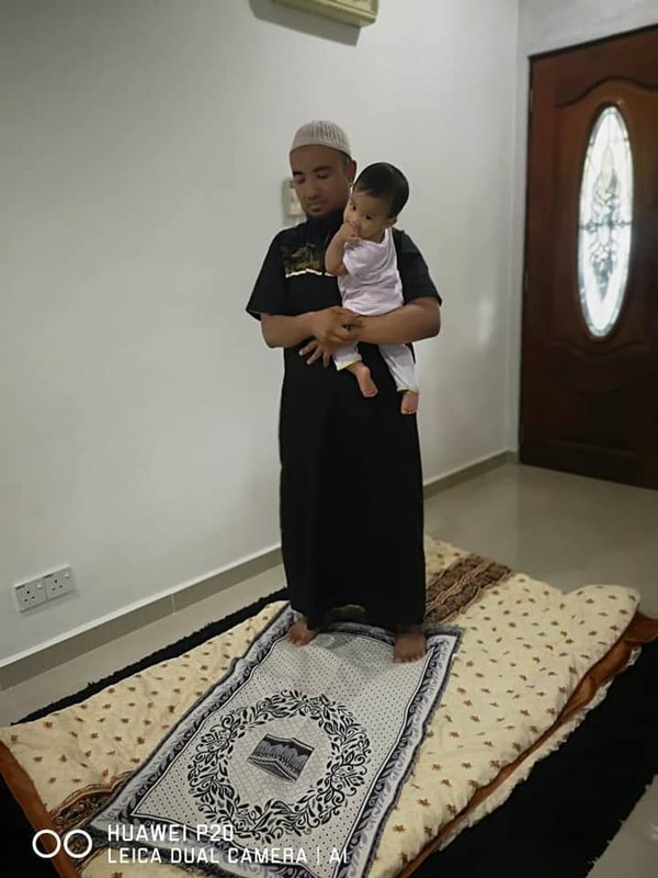 Contoh bapa berdiri dalam solat dengan mendukung anak.