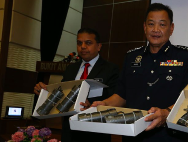 Datuk Seri Abdul Hamid Bador (right) holding up seized explosives.