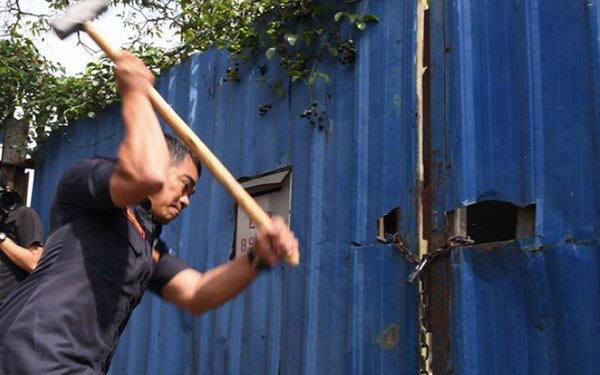 A Klang Municipal Council enforcement officer tries to smash open a lock at an illegal plastic recycling factory in Telok Gong during an operation in January.