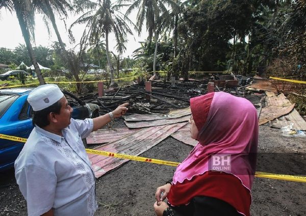 Khamijas Ngainan (left) and his wife (right) in front of the house that burned down.