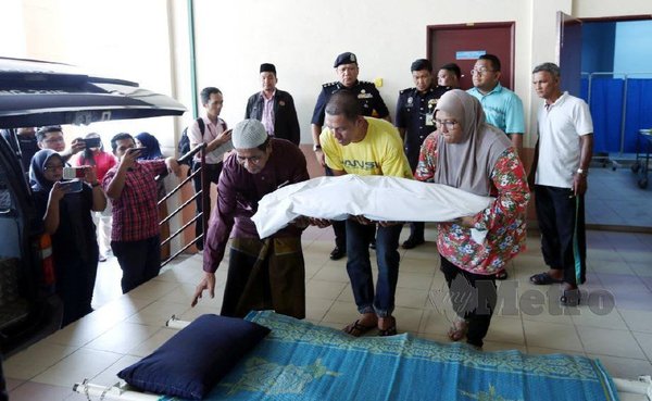 Lans Koperal Ahmad Hafiz Mustafa, 32, (tengah) bersama isterinya, Sofiah Mohd Teridi, 32, memangku jenazah anaknya, Muhamad Anas Hadif, 3, keluar selepas dikapankan di Jabatan Forensik Hospital Raja Permaisuri Bainun Ipoh.