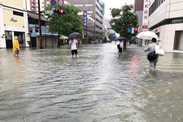 People wading through clear floodwaters in Saga city, Japan.